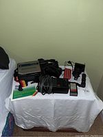 Full lot on table showing Sony Betamovie camcorder, carrying strap, battery charger, power cords, extra battery, and manuals.
