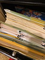 Top view inside drawer showing several folders packed with brochures and folded documents related to football memorabilia.
