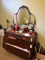 Full view of the wooden dresser with three drawers and attached large oval mirror with carved wooden frame.