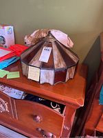 Hanging stained glass lamp shade with brown and beige segments placed on wooden furniture.