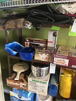 Shelf with various kitchen items including pots, thermos, plastic containers, and boxed appliances.