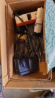 Box containing Lionel train cars, curved and straight tracks, and blue transformer controller.