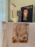 Photo showing various Native American art pieces including dreamcatcher, carved mask on stand, totem pole figurine, stone animal figurine, and calendar.