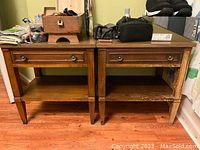Front view of two wooden side tables showing drawer and lower shelf.