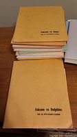 Stack of vintage Falcons vs Rams and Falcons vs Dolphins presskits from 1970 in tan covers.