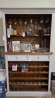 Full view of wine cabinet showing drawers, shelves, hanging glasses, and wooden bottle racks