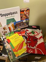 Photo showing assorted World Cup soccer memorabilia including a red and white flag, various books, and visitor guides stacked against a wall.
