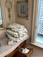 Overview showing framed painting hanging above folded linens on a dresser