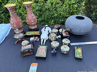 Overview of all items arranged on table showing vases, stone vase, glass bottle, tea set, figurine, boxes and small decorative objects