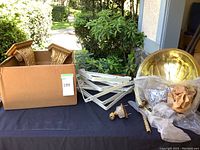 Overview of all components including brass sink, plumbing parts, and shelf brackets on a table.