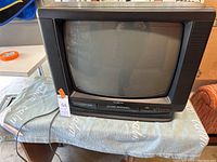 Front view of the Broksonic 19-inch color TV with built-in VHS player sitting on a TV stand covered partially by a blanket.