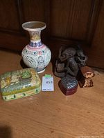 Overview of five items: porcelain vase, wooden sculpture, tin box, heart-shaped box, dog puzzle box