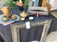 Full view of cast iron fireplace surround on a table with coffee service pieces, ceramic logs and decorative doll figurine