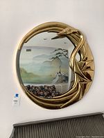 Full view of mirror mounted on wall showing circular reflective surface and decorative gold-tone frame with bird design