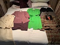 Full lot view: four suits and one dress laid out on bed