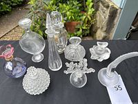 Overview of nine crystal perfume bottles on black cloth outdoors