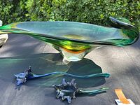 Large green art glass centerpiece and two floral pieces on black surface