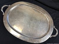 Full view of oval platter on black background showing shape and handles