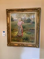 Full view of framed oil painting showing woman raking leaves in a grassy field