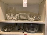 Top shelf and lower shelf display showing six clear crystal bowls including one tall cylindrical, one square-cut, one fluted, one ribbed, one scalloped-edge and one Orrefors Sweden piece.