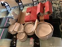 Assortment on table showing red tea cup boxes, zippered cases with soup cups, bird figurines