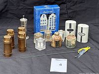 Overview of full lot showing all salt and pepper shakers and decorative bird stick on black background.