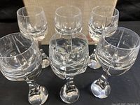 Six clear crystal wine glasses arranged in front of original Baccarat box