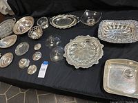 Overview of all silver plate and sterling serving ware on black cloth