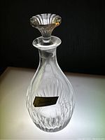 Clear Baccarat crystal decanter with etched vertical swirl pattern, faceted stopper, and label affixed on the body.