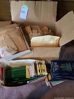 Box filled with numerous envelopes, some containing stamp booklets or magazines, visible green travel magazines, and a box set of Joseph Campbell VHS cassettes