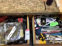 Two drawers open side-by-side showing a drawer filled with sunglasses, readers, and cases and another drawer with flatware and costume jewelry.