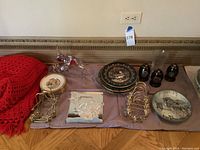 Overview of lot showing Swarovski crystal fish sculpture, decorative plates, and black decorative eggs on gold-tone stands arranged on table