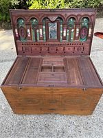 Opened trunk showing carved lid interior with green felt backing, floral decals and central mirror