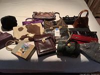 Multiple handbags and clutches arranged on bed showing overall assortment