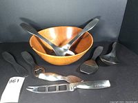 Full lot showing 6 stainless steel serving pieces with one butternut wood salad bowl and two additional stainless steel pieces to the side.