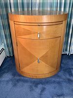 Front view of nightstand showing diamond harlequin veneer pattern and metal teardrop pulls.