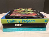 Stack of four hardcover Chihuly art glass books showing spines: Chihuly Persians, Chihuly Projects, Chihuly by Donald B. Kuspit, and Chihuly: Baskets