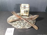 Top view of two round trivets, salad servers (fork and spoon), and salt & pepper caddy.