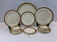Assorted dinnerware displayed on white backdrop including plates, cups, saucers