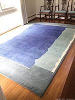 Front view of rug laid out in dining area showing full abstract pattern