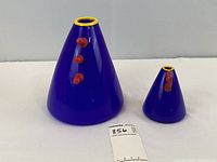 Overview of two cobalt blue conical glass vases with red applied decorations and yellow rims