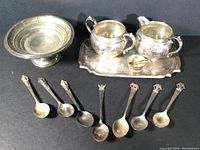 All lot items displayed: bonbon dish, creamer, sugar bowls, tray, tongs, and seven spoons