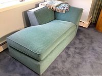 Front view of green upholstered one-arm chaise lounge with a blanket draped over the top, showing overall condition and structure.