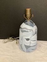 Front view of vintage glass table lamp showing swirl pattern and brass socket with electrical cord.