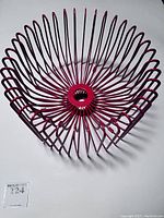 Top-angle photo showing circular wire frame radiating from center with original plastic clips on bottom of bowl, well maintained red finish.