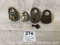 Four padlocks and one key arranged on fabric with lot number tag.