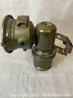 Side view of the antique brass coach light showing the lens, green side reflector, and mounting bracket.