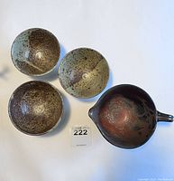 Top view of set showing three small speckled bowls and a larger pitcher with handle and spout