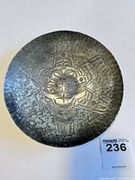 Top-down view of the silver plate bowl showing the stamped sun design with detailed facial features and wings/rays extending outward.