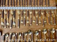 Multiple forks with rosewood handles and brass ferrules laid in rows on wood surface.